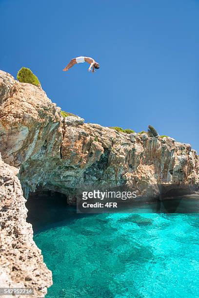 Mann springen auf einer Klippe ins Meer, Mallorca, Spanien