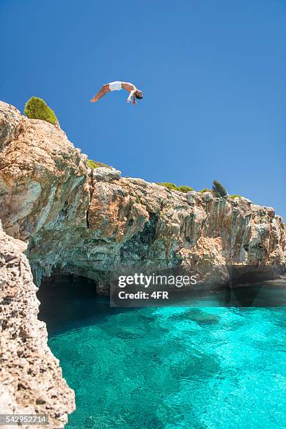 ragazzo saltando su una roccia nell'oceano, maiorca, spagna - tuffi dalle rocce foto e immagini stock