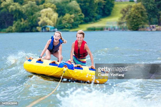 boy and girl children tubing on minnesota lake in summer - minnesota lake stock pictures, royalty-free photos & images