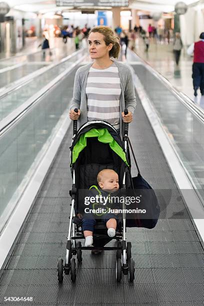 mujer empujando un paseante en el aeropuerto - departure board front on fotografías e imágenes de stock