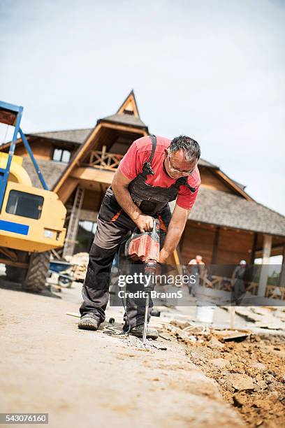 senior worker demolishing the concrete with a drill. - jackhammer stock pictures, royalty-free photos & images