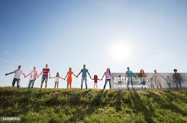 large group of happy people holding hands against the sky. - people in a row stock pictures, royalty-free photos & images