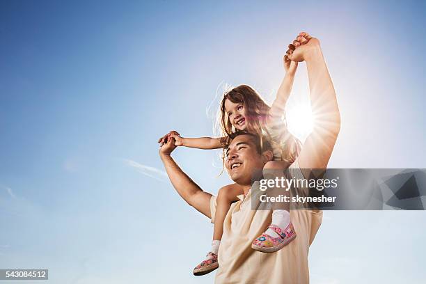 asian father carrying daughter on shoulders against the blue sky. - kid looking up to the sky stock pictures, royalty-free photos & images