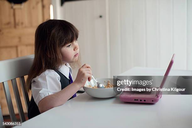 school girl watching a portable dvd at breakfast - dvd player stock pictures, royalty-free photos & images