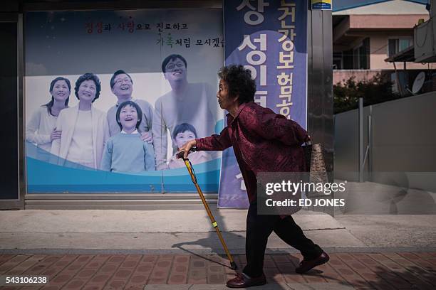 In a photo taken on May 27, 2016 an elderly woman walks past a poster at a health centre in Gunwi, some 200 kilometres south of Seoul. By 2030, a...
