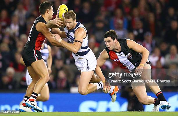 Lachie Henderson of the Cats is tackled by Paddy McCartin of the Saints and Darren Minchington of the Saints during the round 14 AFL match between...
