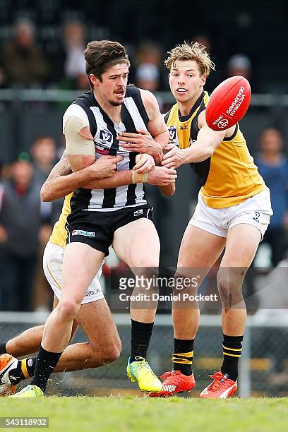 Ryan Pendlebury of the Magpies handballs whilst being tackled during the round 12 VFL match between the Collingwood Magpies and the Richmond Tigers...