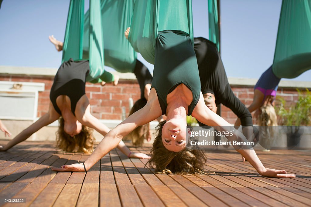 A group performs aerial yoga.