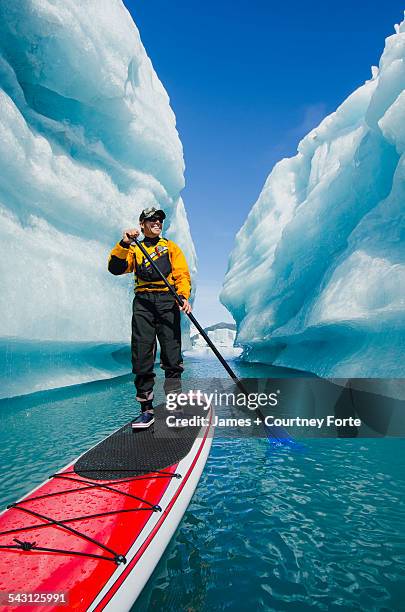 a man on stand up paddle board (sup) explores an iceberg canyon on bear lake in kenai fjords national park, alaska. - paddle board men imagens e fotografias de stock