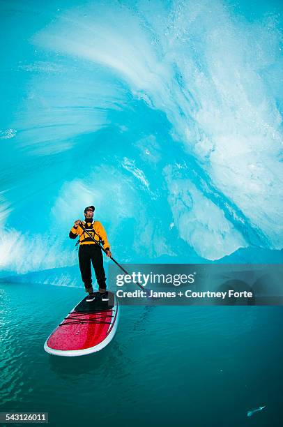 one man on stand up paddle board (sup) maneuvers in an iceberg cavern on bear lake in kenai fjords national park, alaska. - paddle board men imagens e fotografias de stock