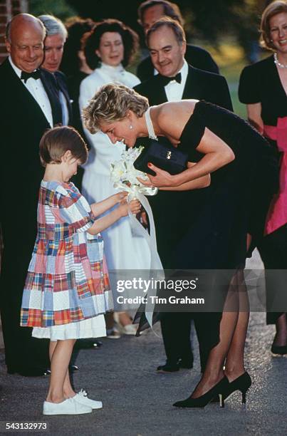 Princess Diana receives a bouquet from a young girl, as she arrives for a gala event at the Serpentine Gallery, London, 29th June 1994. The princess...