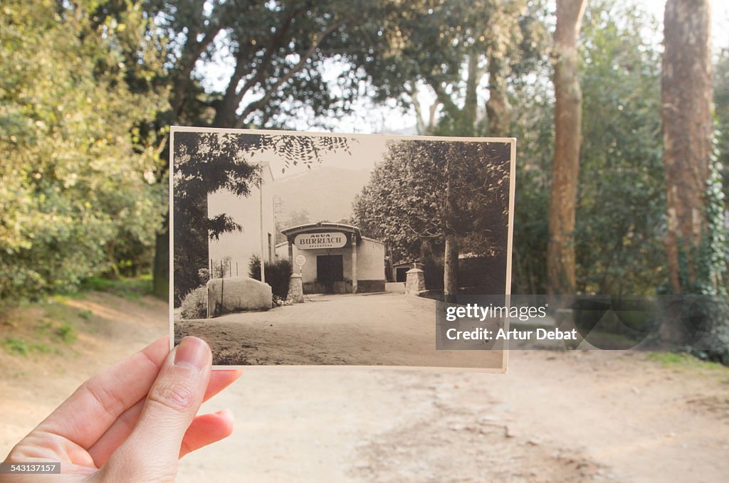 Now and then, holding picture by hand on nature.