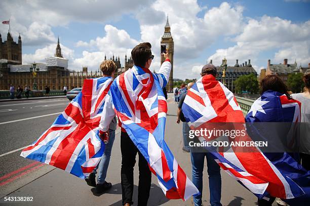 People walk over Westminster Bridge wrapped in Union flags, towards the Queen Elizabeth Tower and The Houses of Parliament in central London on June...