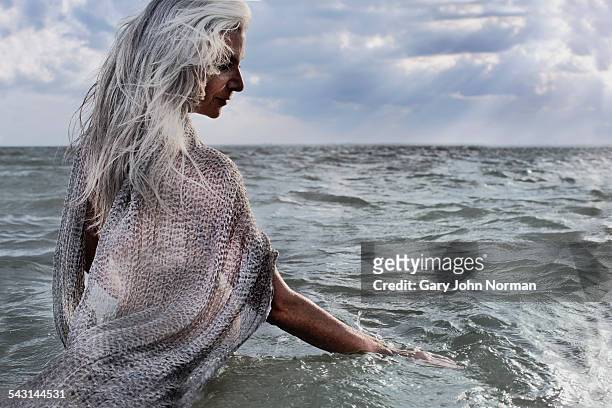 senior woman with grey hair standing in the ocean - mature woman in water stock pictures, royalty-free photos & images