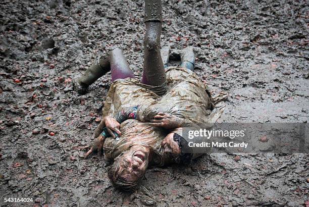 Two festival revellers roll in the mud after they took part in a tomato fight at the Glastonbury Festival 2016 at Worthy Farm, Pilton on June 25,...