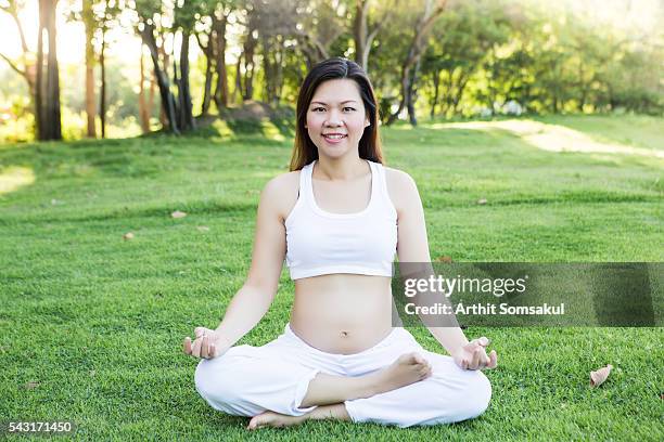 pregnant woman sitting in half lotus position meditating - halber lotussitz stock-fotos und bilder