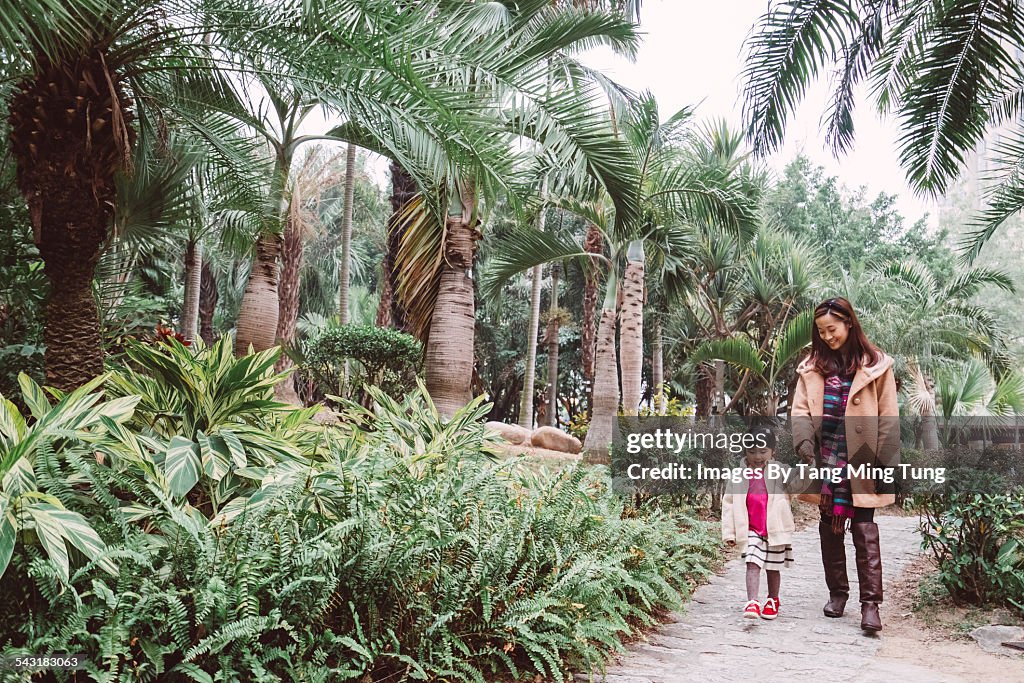 Young mom and daughter strolling in the park