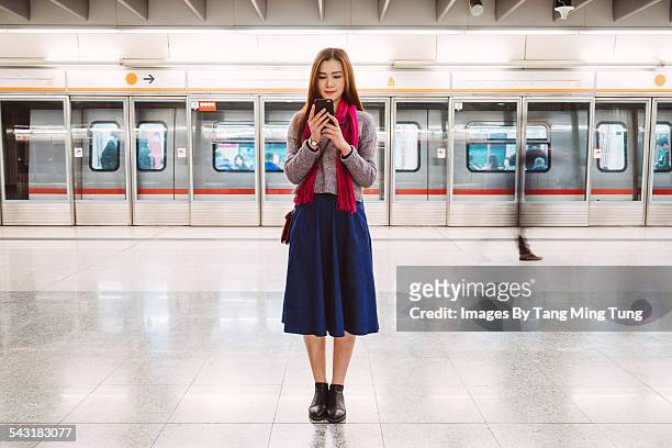 young lady using smartphone on train platform - railroad station platform stockfoto's en -beelden