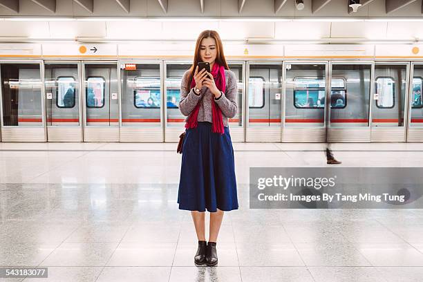 young lady using smartphone on train platform - skirt stock pictures, royalty-free photos & images