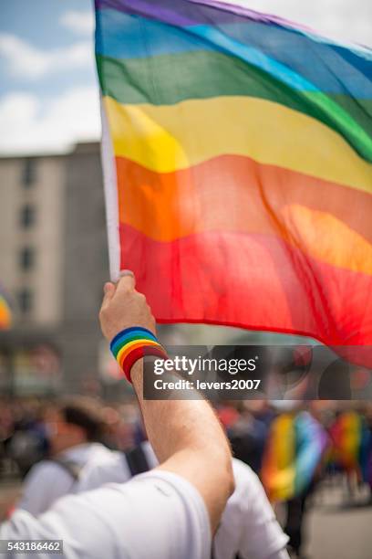 rainbow gay pride flag and wristband in pride parade - pride stock pictures, royalty-free photos & images