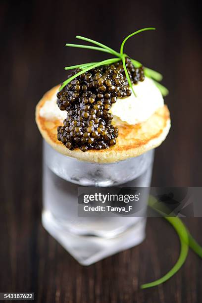 blini and real black caviar appetizre with vodka - amuse bouche stockfoto's en -beelden