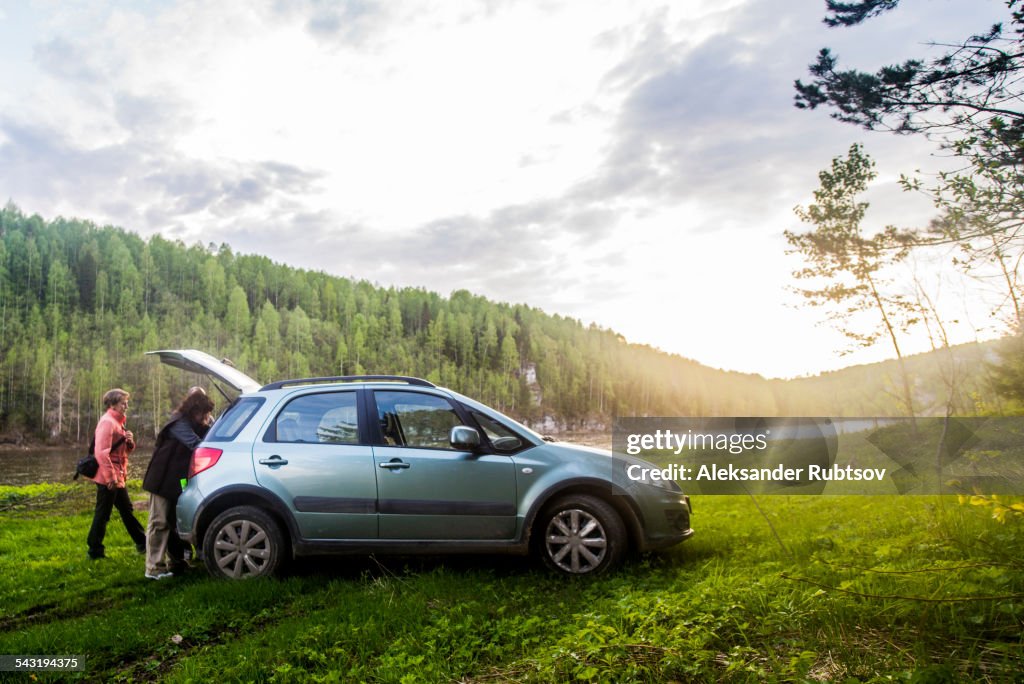 Caucasian tourists unloading car in remote landscape