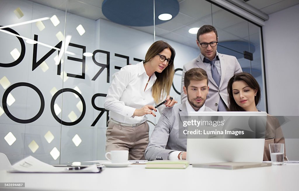 Caucasian business people using laptop in office meeting