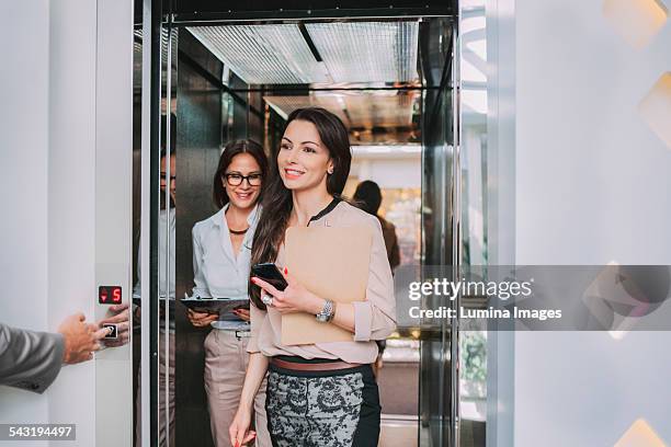 caucasian businesswomen walking out of elevator - lift button stock pictures, royalty-free photos & images