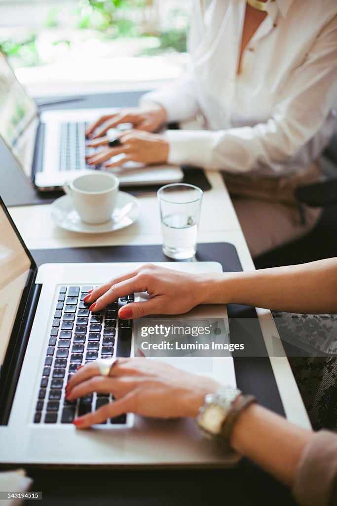 Caucasian businesswomen working at laptops at desk