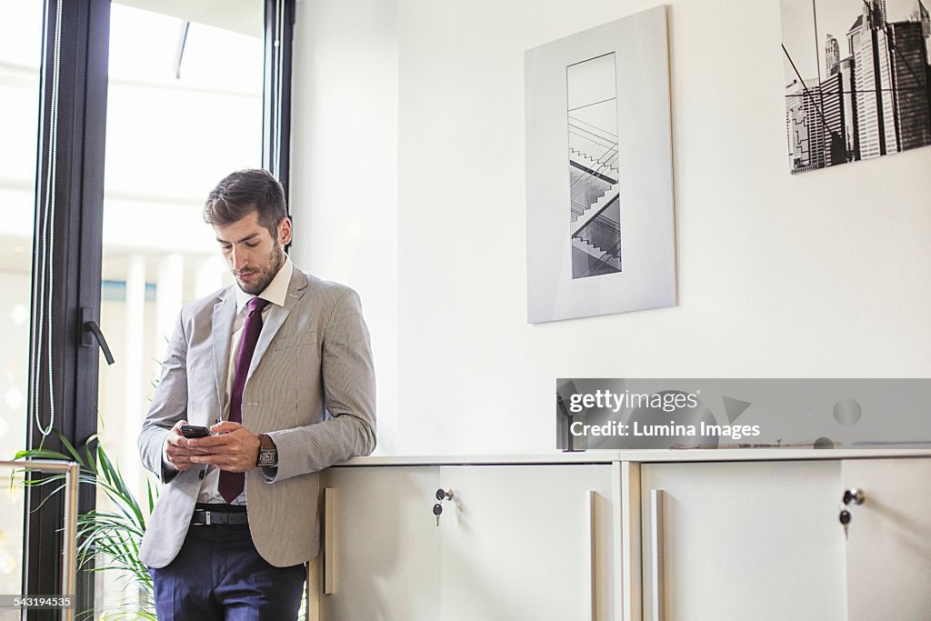 Caucasian businessman using cell phone in office