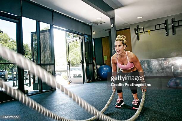 Caucasian woman working out with ropes in gym