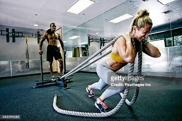 people working out with ropes in gym - crossfit stockfoto's en -beelden