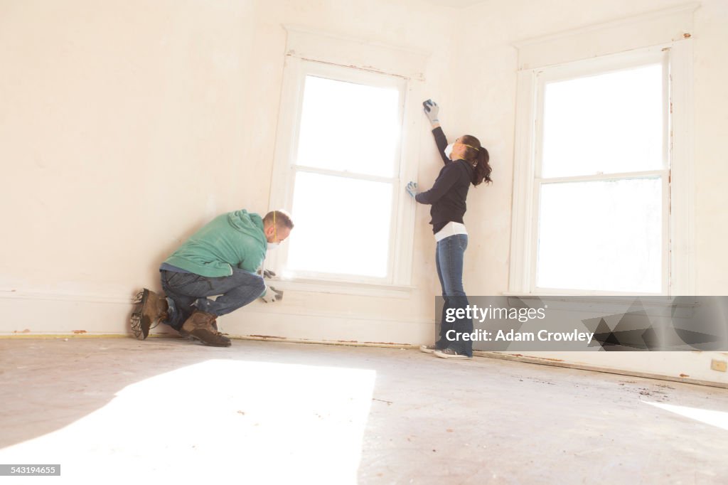 Mixed race couple cleaning wall new home