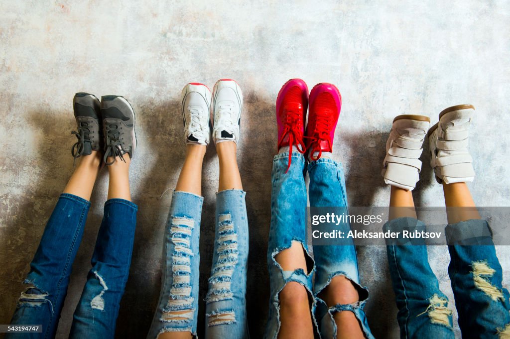 Caucasian women admiring their sneakers against wall