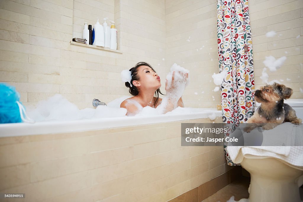Chinese woman playing in bubble bath with dog