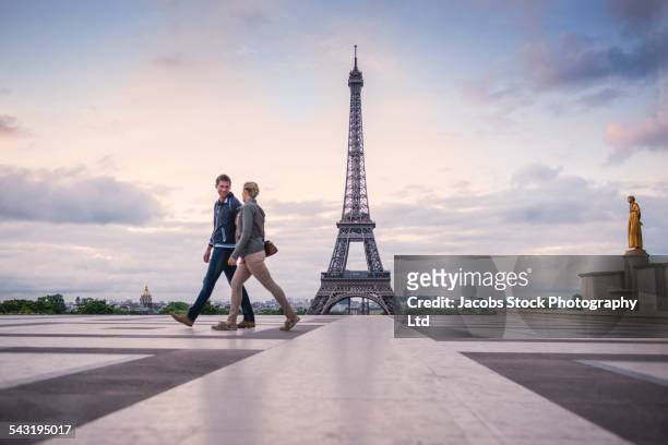caucasian couple walking near eiffel tower, paris, france - couple paris stockfoto's en -beelden