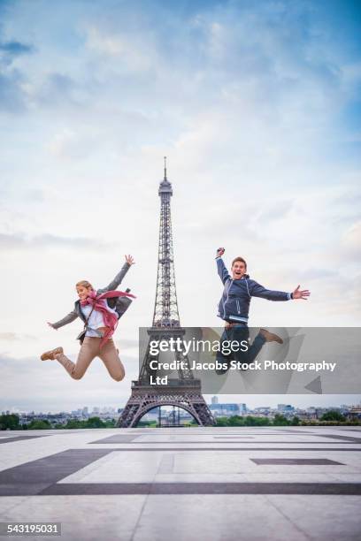 caucasian couple posing near eiffel tower, paris, france - eiffel tower tourists stock pictures, royalty-free photos & images