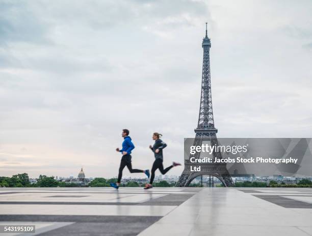 caucasian couple running near eiffel tower, paris, france - jogging photos et images de collection