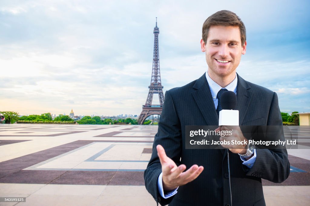 Caucasian news reporter talking near Eiffel Tower, Paris, France