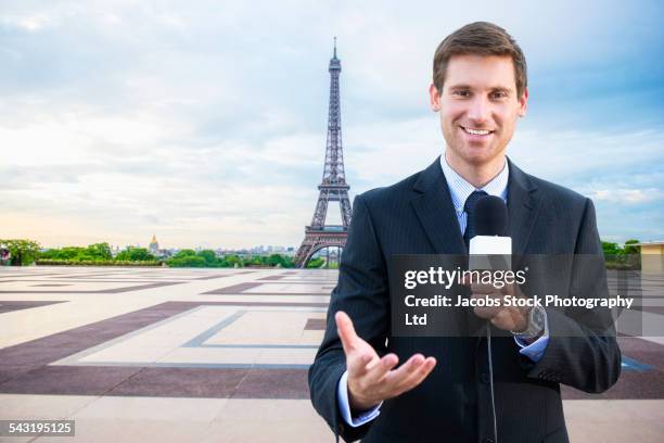 caucasian news reporter talking near eiffel tower, paris, france - holding microphone stock pictures, royalty-free photos & images