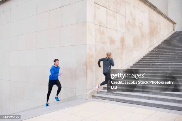 caucasian couple running up staircase - running paris stock-fotos und bilder