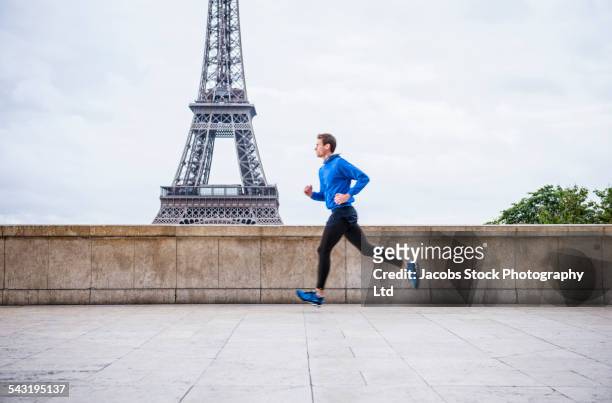 caucasian man running near eiffel tower, paris, france - jogging photos et images de collection
