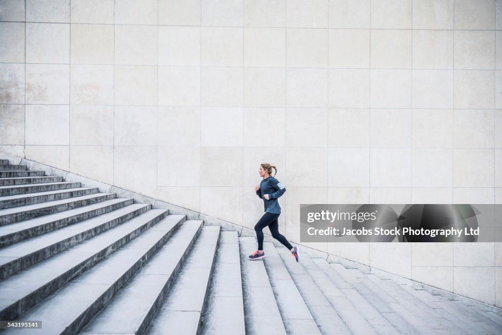 Caucasian woman running up staircase