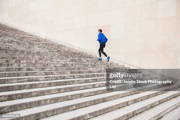caucasian man running up staircase - running paris stock-fotos und bilder