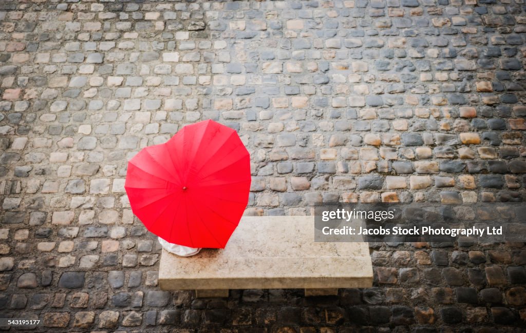 Caucasian woman sitting under heart shape umbrella