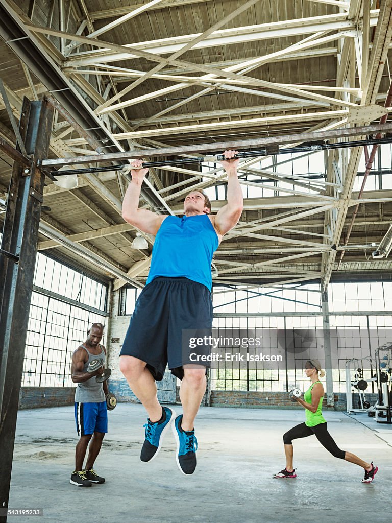 Athlete doing pull-ups in warehouse gym