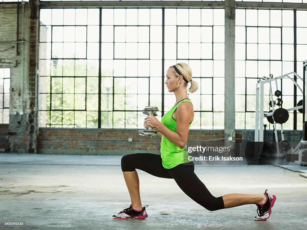 Caucasian woman lifting weights in warehouse gym