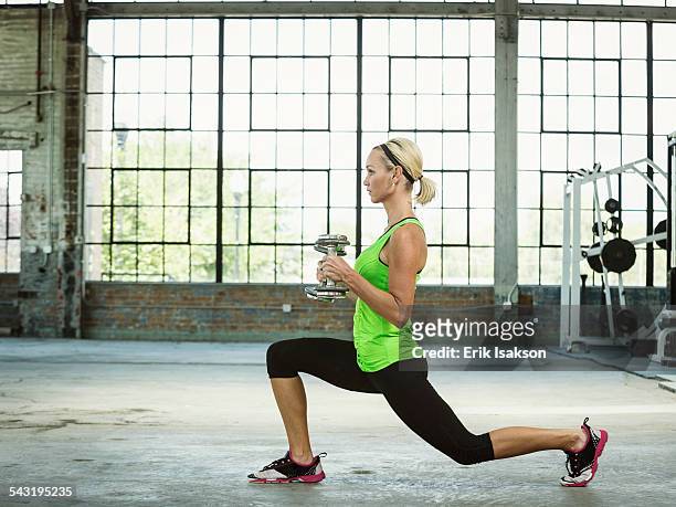 caucasian woman lifting weights in warehouse gym - lunge imagens e fotografias de stock