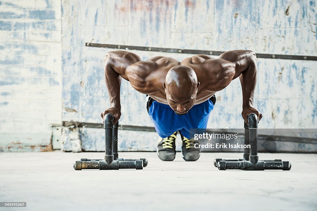 Black man doing push ups in warehouse