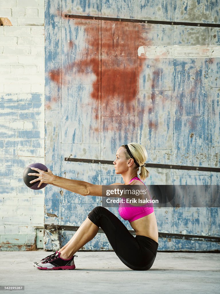 Caucasian woman lifting weights in warehouse
